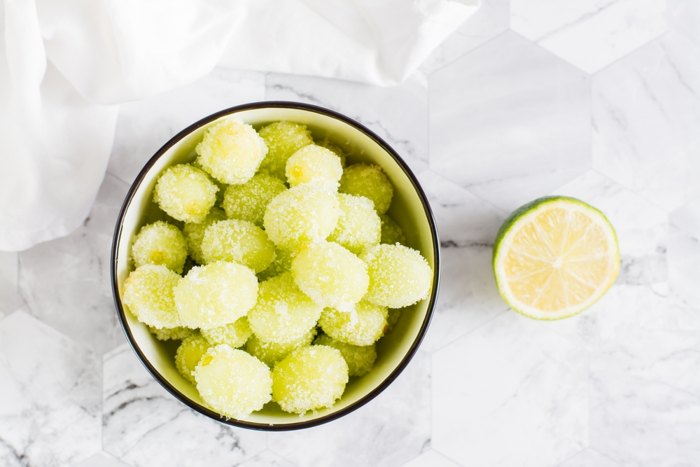 Sour candy grapes in a bowl and cooking ingredients on the table. Social media candy trend. Top view. Close-up