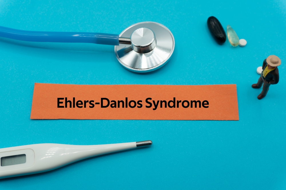 Ehlers Danlos Syndrome.The word is written on a slip of colored paper. health terms, health care words, medical terminology. wellness Buzzwords. disease acronyms.