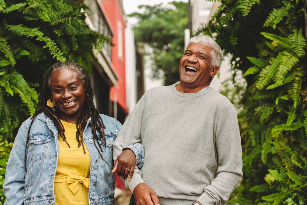 Romantic senior couple laughing cheerfully while walking together outdoors. Happy senior couple spending some quality time together after retirement.