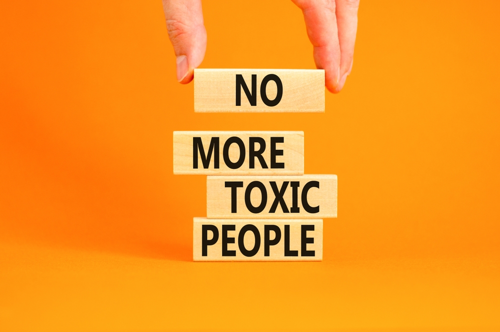 No more toxic people symbol. Concept words No more toxic people on wooden blocks on a beautiful orange table orange background. Psychologist hand. Business, psychological no more toxic people concept.