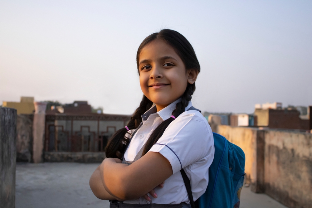 Confident rural Indian school girl standing with backpack