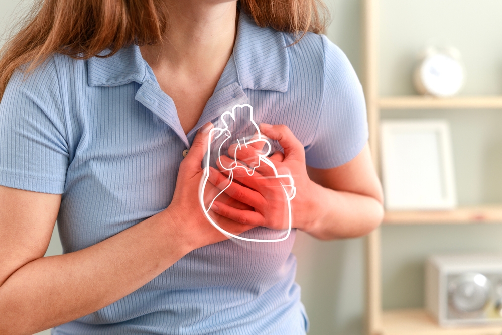 Young woman pressing on chest with painful expression. Severe heartache, having heart attack or painful cramps, heart disease.
