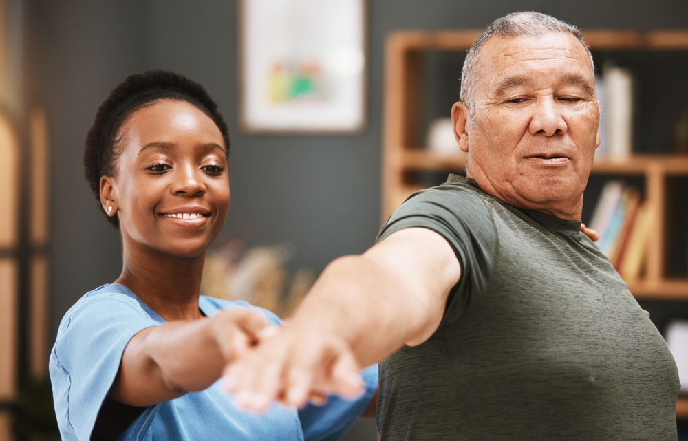Patient stretching, physiotherapist black woman and physical therapy help for muscle or arthritis exercise in consulting exam. Physiotherapy, chiropractor and healthcare rehabilitation support of man
