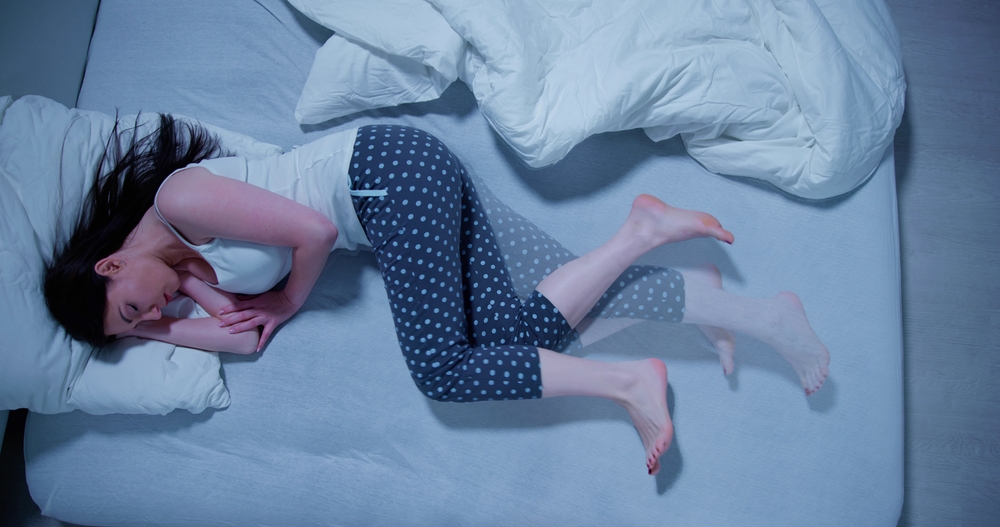 Woman With RLS - Restless Legs Syndrome. Sleeping In Bed