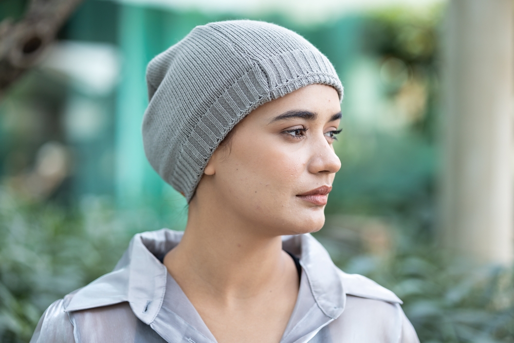 Sad and depressed south asian woman cancer patient with concealing head scarf, suffering from serious hair loss due to chemotherapy negative side effect