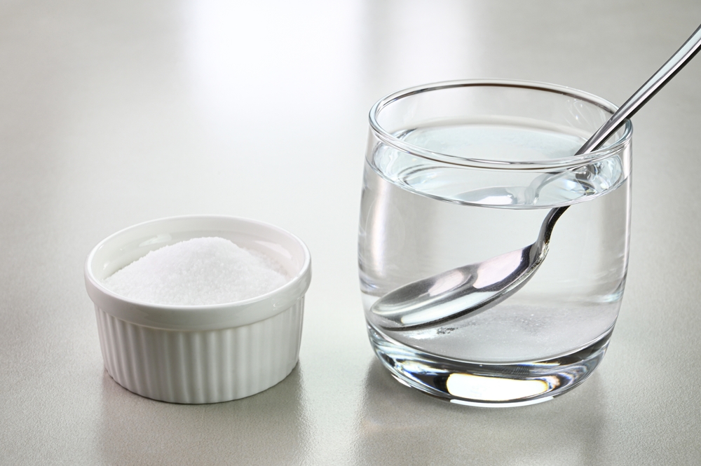 Salt water in a glass cup and salt in a bowl.