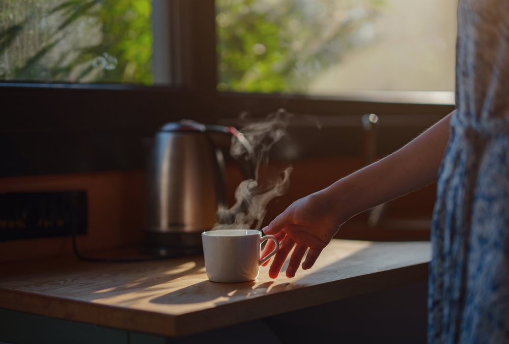 Woman is drinking coffee , morning routine. Tiny house. First property. Small apartment interior design. Minimalism. Moving in. Living alone. Charming trailer house with the morning sun
