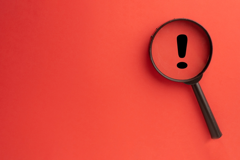 Exclamation mark concept.,Magnifying glass focus on Exclamation mark icon over red background with copyspace for put your text or logo.