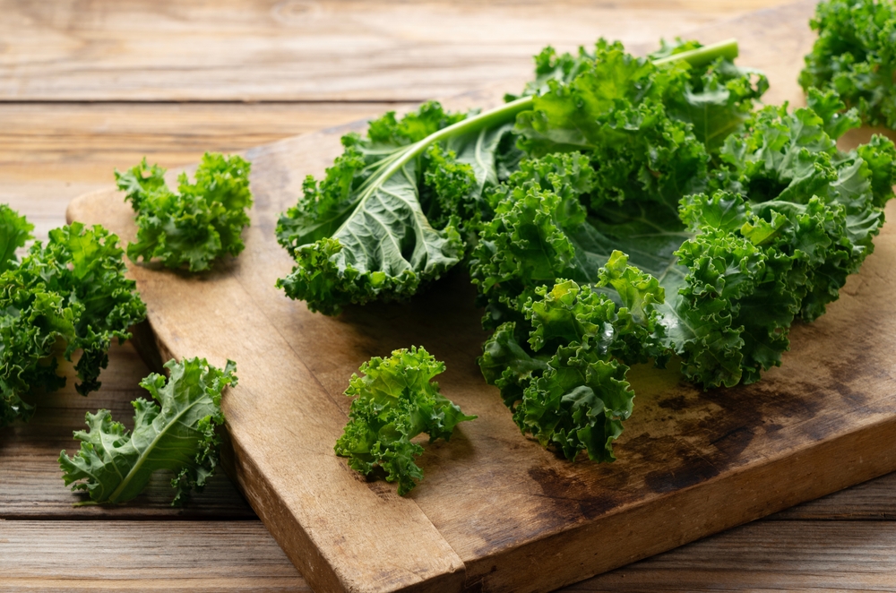 Cutting board and kale on wooden background. curly kale. Close-up.