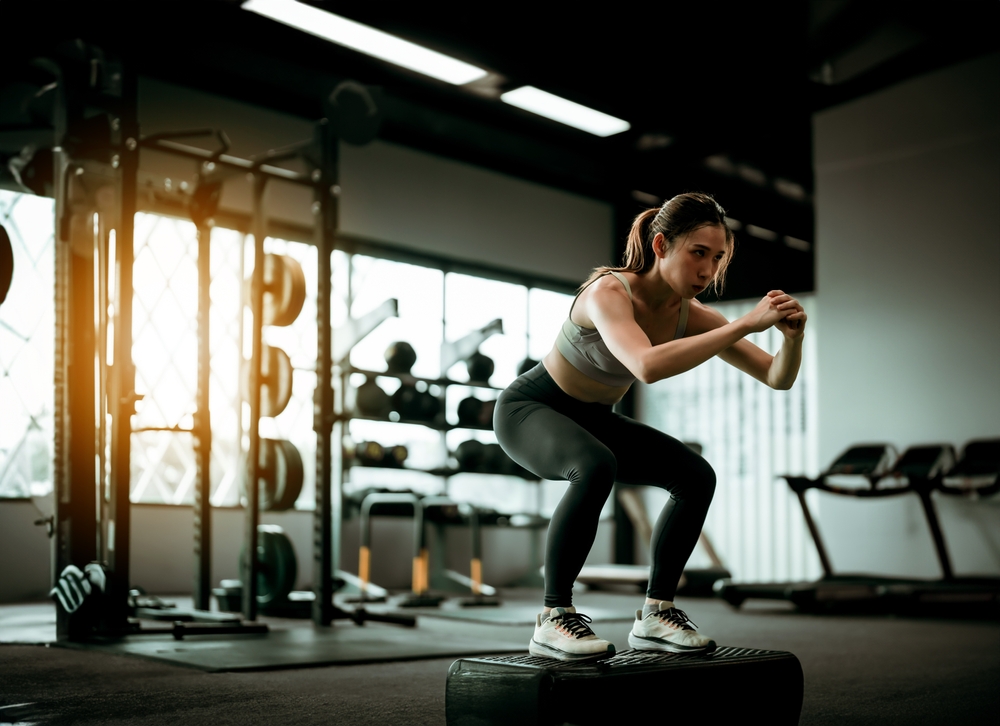 Young Sportive Woman Workout Exercising with Jumping Step Platform at Fitness Center or Gym. Fitness and Wellness Concept
