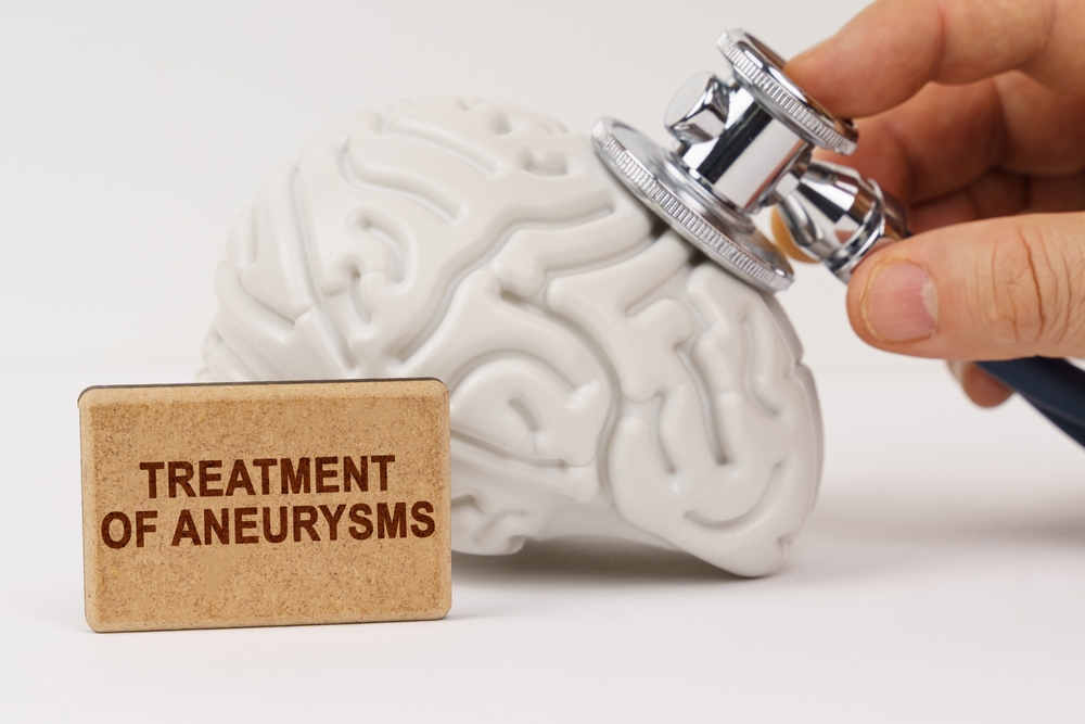 Medical concept. On a white surface, the brain is diagnosed using a stethoscope, next to it is a sign with the inscription - Treatment of aneurysms