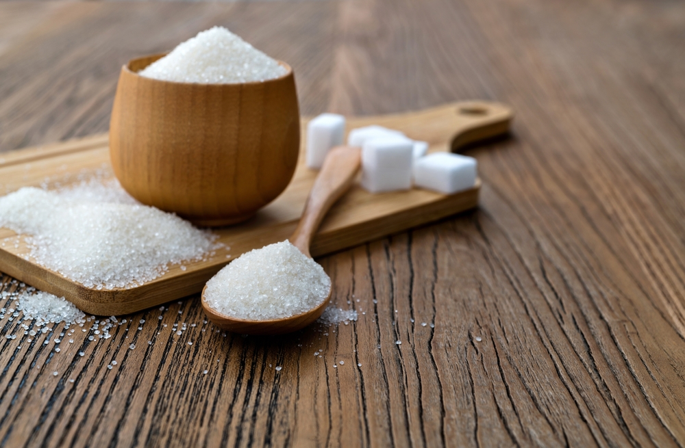 A bowl granulated sugar and sugar cubes on the board.