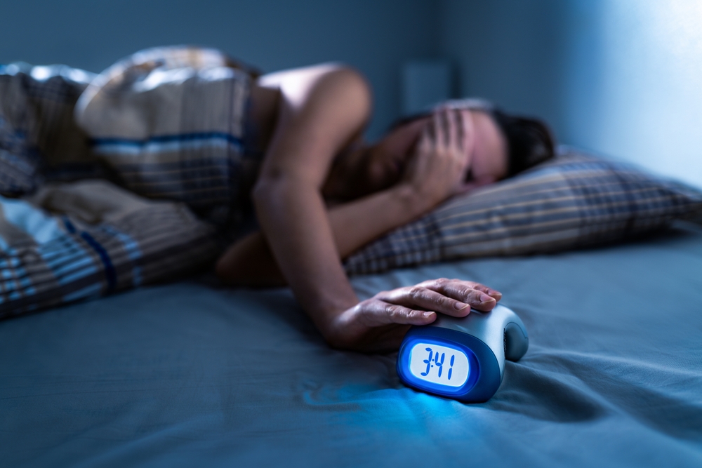 Insomnia and sleep. Sleepless woman. Bad night. Trouble and disorder in bed. Dream problem or lack. Alarm clock. Not asleep, lying awake. Anxiety or nightmare. Sad girl with stress or pain. Insomniac.
