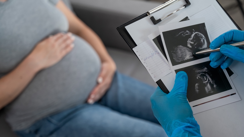 Gynecologist looks at an ultrasound of a pregnant woman.