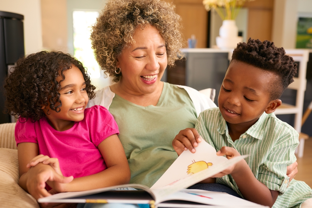 Grandmother Looking After Grandchildren At Home Reading A Story Together