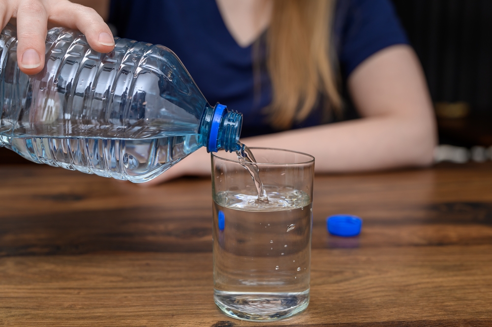 Pour mineral water from a plastic bottle into a glass
