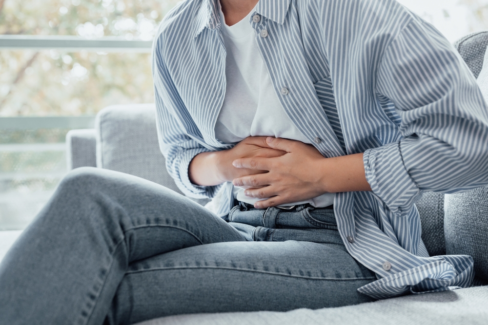 Sick young woman in pain holding belly stomach feeling hurt abdomen ache gastritis pancreatitis symptoms or diarrhea, upset teen girl suffering from indigestion flatulence abdominal problem concept
