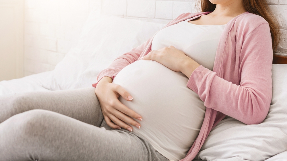 Pregnancy and rest. Young millennial pregnant woman lying in bed, panorama with free space
