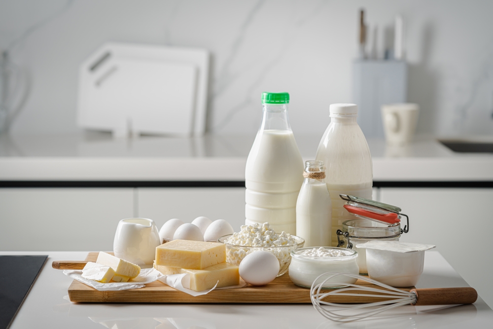 Fresh dairy products, milk, cottage cheese, eggs, yogurt, sour cream and butter on kitchen table
