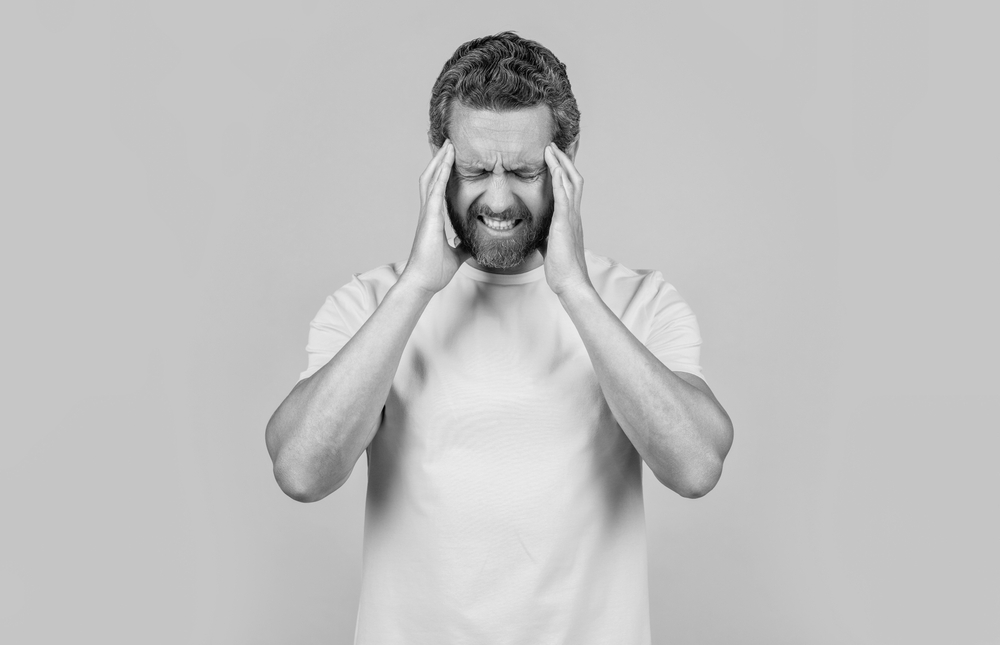 man has headache on yellow background. man has headache in studio.
