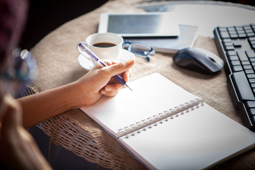 woman left hand writing on paper book ,on table shot