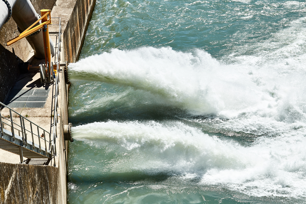 Discharge water from dam in the Alps. Drain the water from the dam in the mountains. The dam closeup.
