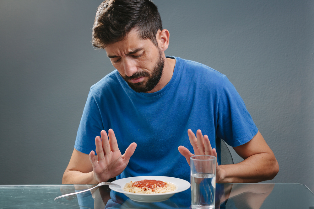 Portrait of man with no appetite in front of the meal. Concept of loss of appetite
