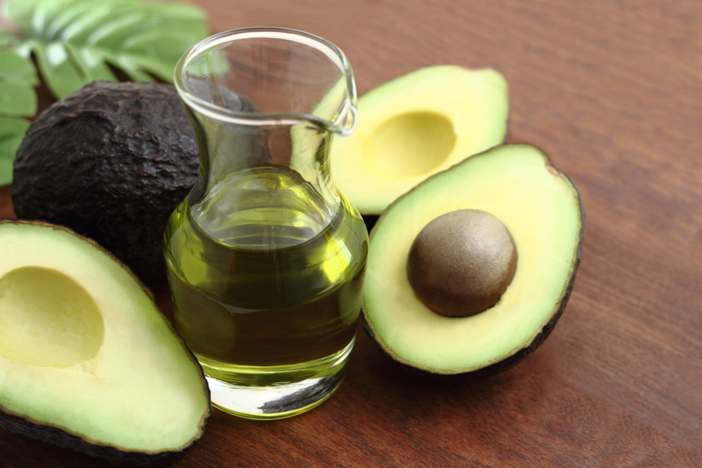 Three fresh avocado and avocado oil on wooden table/ Avocado and avocado oil