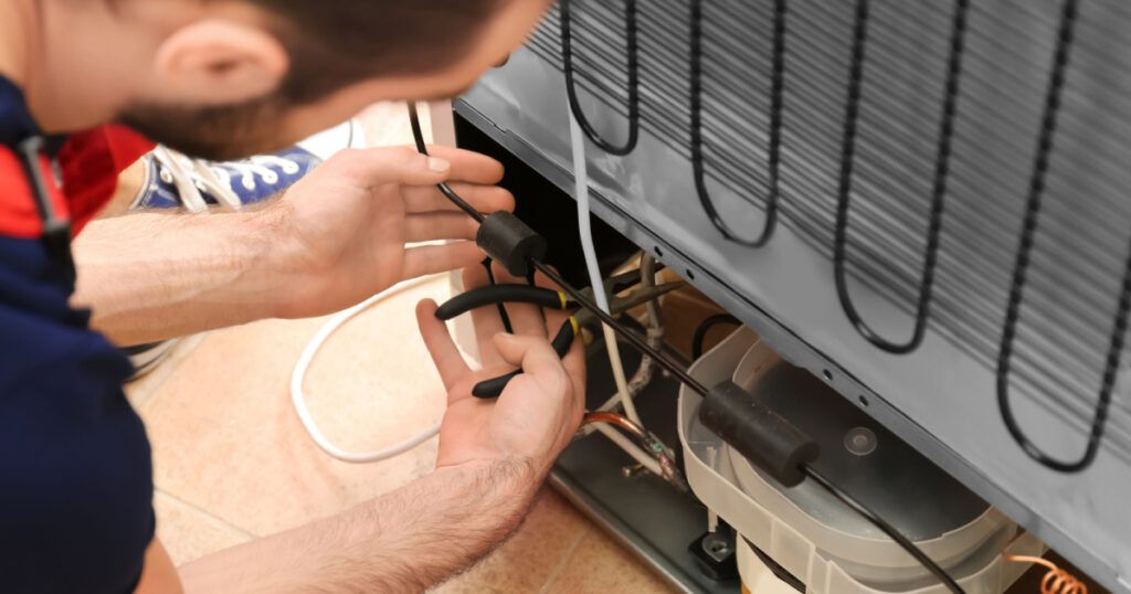 Male technician repairing refrigerator indoors