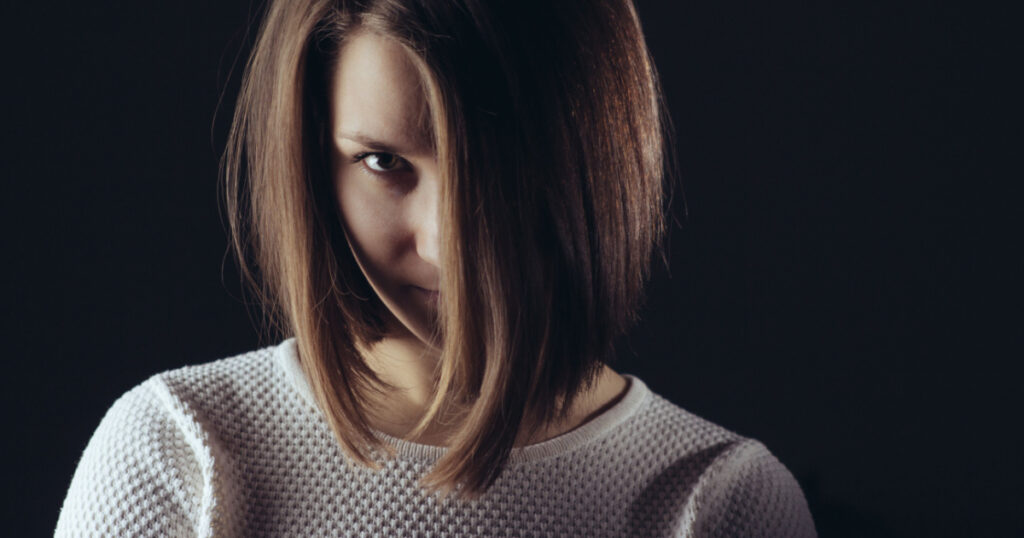 Woman hair covered face portrait in studio on dark background