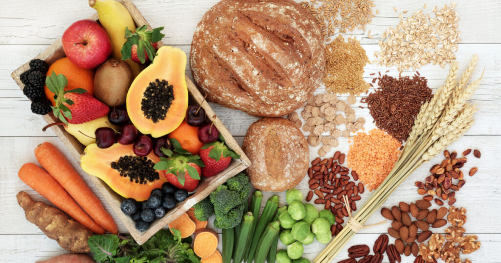 Healthy high fibre diet food concept with legumes, fruit, vegetables, wholegrain bread, cereals, grains, nuts and seeds. Super foods high in antioxidants, anthocyanins, omega 3 and vitamins. Top view.