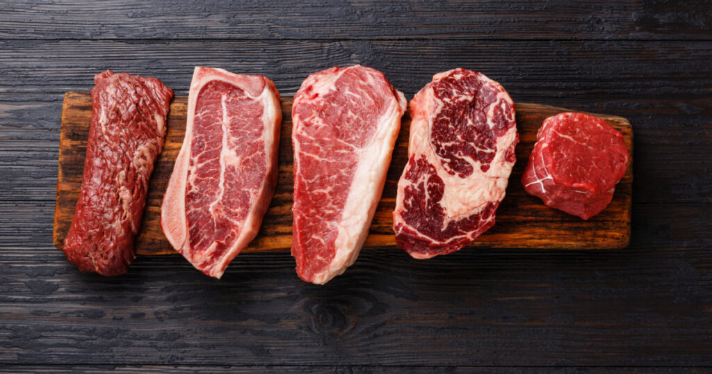 Variety of Raw Black Angus Prime meat steaks Machete, Blade on bone, Striploin, Rib eye, Tenderloin fillet mignon on wooden board copy space