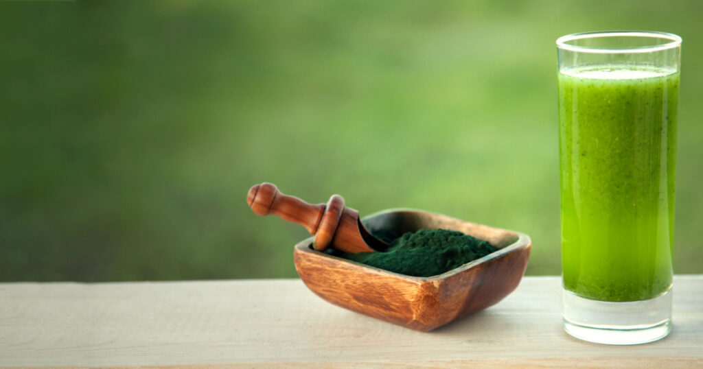Green smoothie with spirulina on wood background