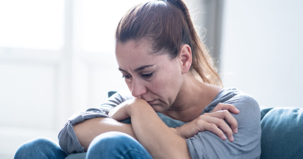 Young attractive latin woman lying at home living room couch feeling sad tired and worried suffering depression in mental health, problems and broken heart concept.