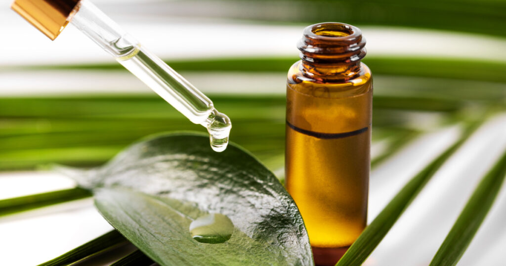 essential oil dripping on the green leaf from pipette