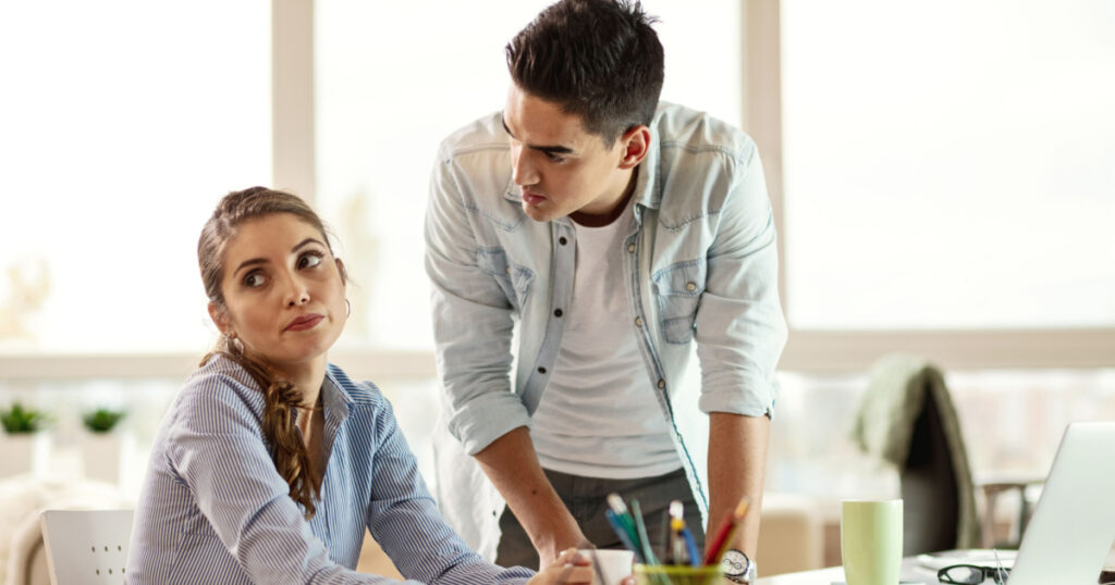 Young businesswoman feeling tired of listening her annoying boss who is scolding her in the office.