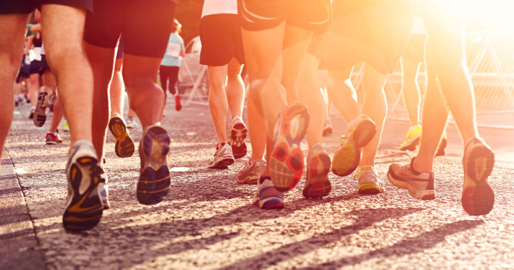 Marathon running race people competing in fitness and healthy active lifestyle feet on road