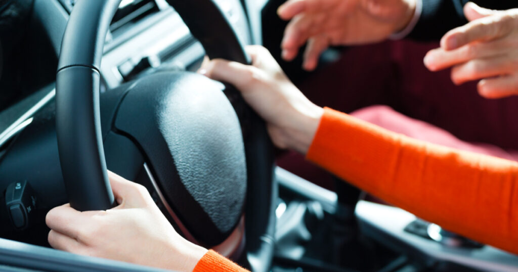Driving School - Young woman steer a car with the steering wheel, maybe she has a driving test perhaps she exercises the parking