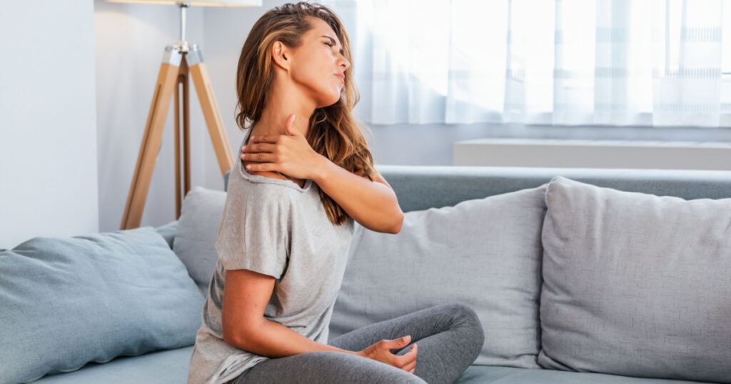 Pain in the shoulder. Upper arm pain, People with body-muscles problem, Healthcare And Medicine concept. Attractive woman sitting on the bed and holding painful shoulder with another hand.