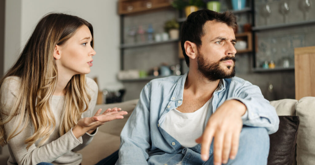 Young woman asking her boyfriend for forgiveness at home