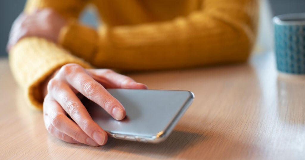 Woman Concerned About Excessive Use Of Social Media Laying Mobile Phone Down On Table