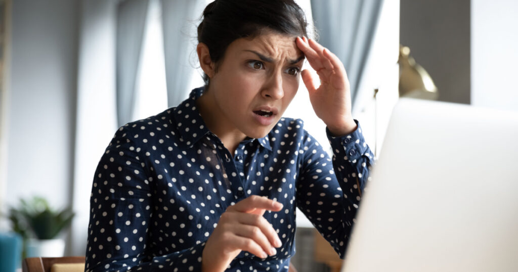 Shocked afraid worried young indian girl look at laptop computer screen terrified read bullying social media message feel bad surprise stress panic about stuck computer problem concept at home office