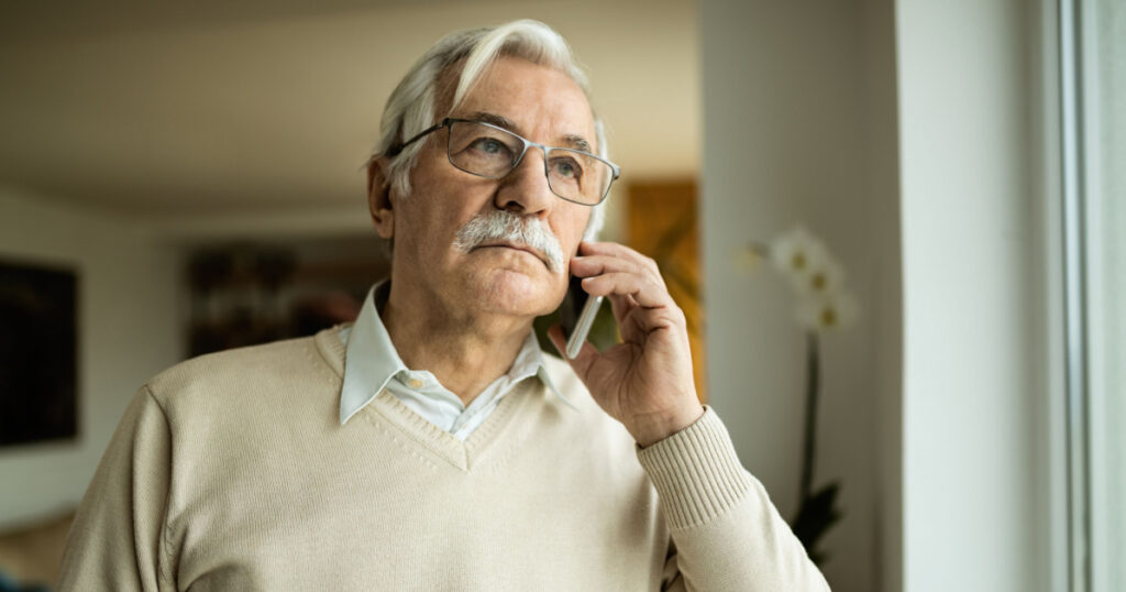 Pensive mature man communicating with someone over mobile phone.