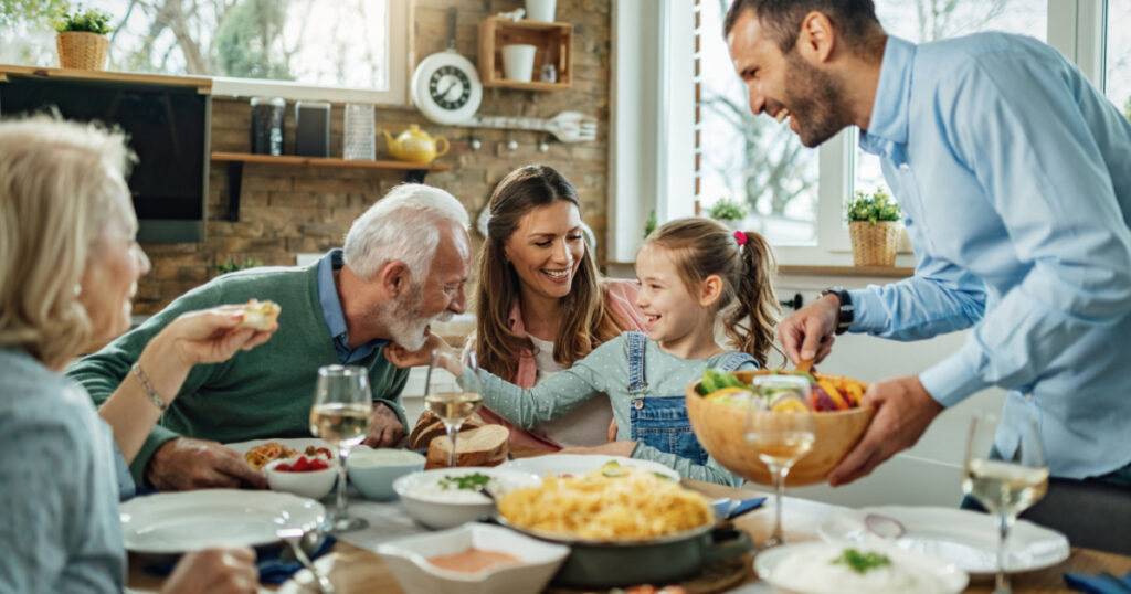 Happy multi-generation family gathering around dining table and having fun during a lunch.
