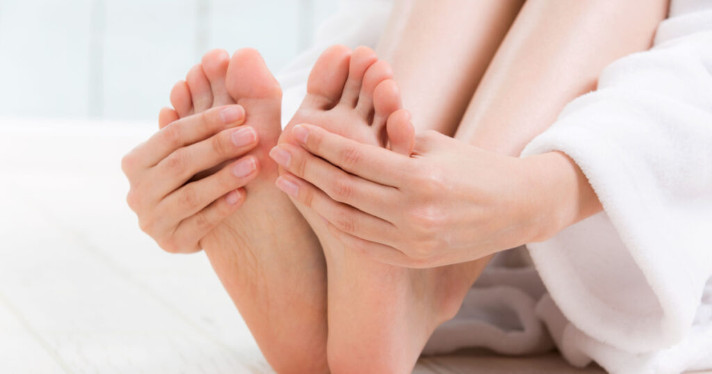 A woman is touching her sole.