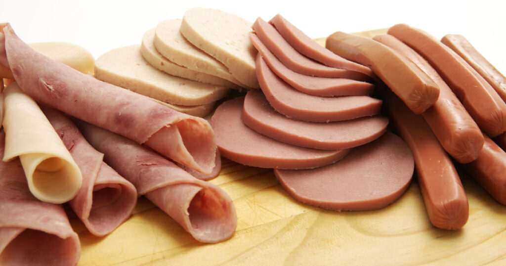 A collection of cold meats and vienna on a wooden board in a studio