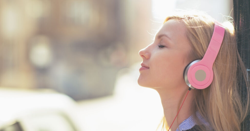 Young woman listening music in headphones in the city