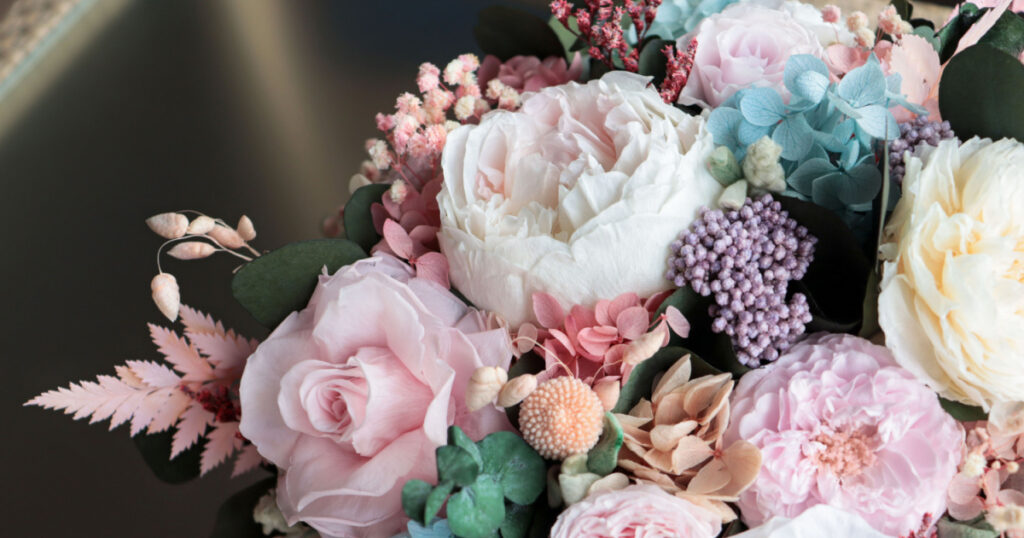 Beautiful flower arrangement in a white box. Flower shop concept. Floristics preserved flowers. White rose, mixed roses flowers, peony, blue hydrangea and eucalyptus.