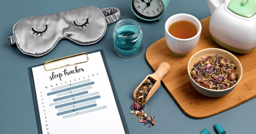 Classic alarm clock, sleeping mask, sleep tracker and herbal tea on blue background. Minimal concept of rest, quality of sleep, good night, insomnia, relaxation. Copy space