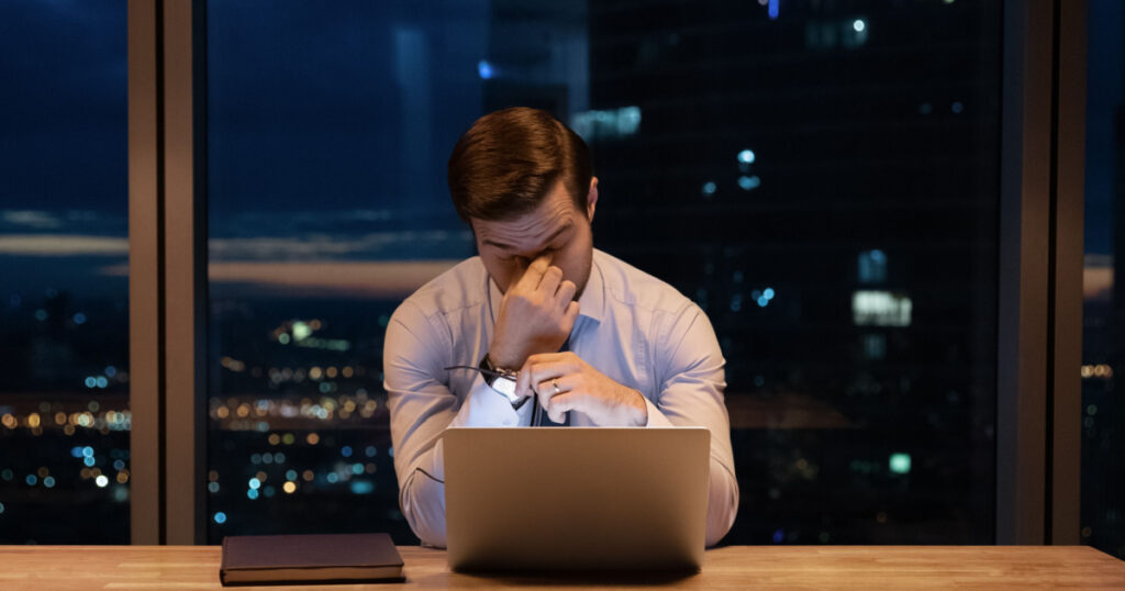 Need some rest. Overworked young man ceo manager take break in online work close tired eyes rub nose bridge. Busy office employee suffer from chronic dry eye syndrome spending hours in front of laptop